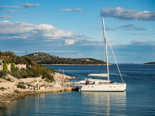 Fototapeta na wymiar Kaprije island, Croatia: [ Catamaran docked in a bay with restaurant at sunset, Croatian landscape ]