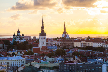 Fototapeta premium Orange sunset over old town of Tallinn, Estonia. Cathedrals towers and medieval buildings aerial view.
