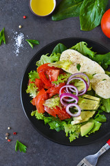 Vegetable salad with mozzarella, tomatoes and avocado on a black background