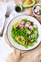 Mix salad with cucumber, avocado, green peas and flax seeds on a marble background