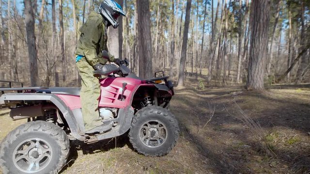 The racer in the wood. The man on the ATV. The man in a special form and a helmet quietly rides the ATV on forest roads.
