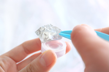 Female hands taking contact lens from container, closeup