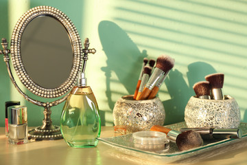 Decorated mirror, brushes, perfume and cosmetics on table