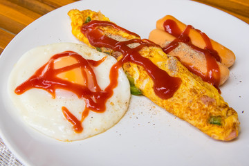 Eggs Sunny Side Up, Sausage and Omelet with tomato sauce put in a white dish  for breakfast.