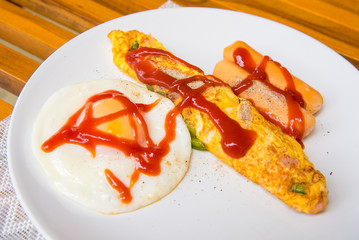 Omelet, grilled sausages, tomato on a white plate.