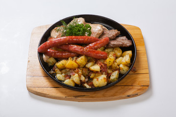 grilled sausages with potatoes, and roasted meat on a grill pan