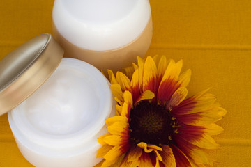 Cosmetic cream container and yellow flowers.