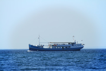 A ship with tourists is sailing on the sea. They are having a good time.