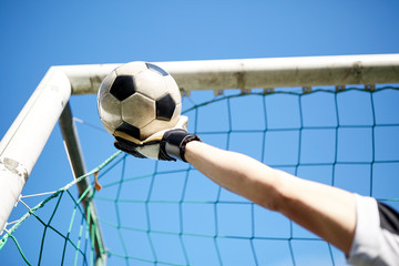 goalkeeper with ball at football goal over sky