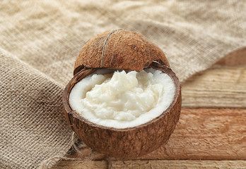 Fresh coconut oil in half of nut on wooden table