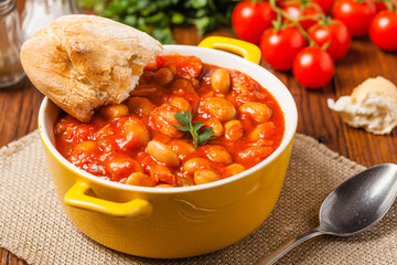 Baked beans in tomato sauce served in yellow, clay bowls.