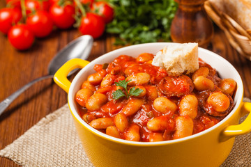 Baked beans in tomato sauce served in yellow, clay bowls.