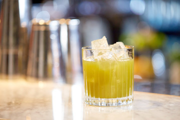glass of cocktail with ice cubes at bar