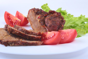 Steak of grilled meat with tomato, lettuce and beans pomegranate on white plate.