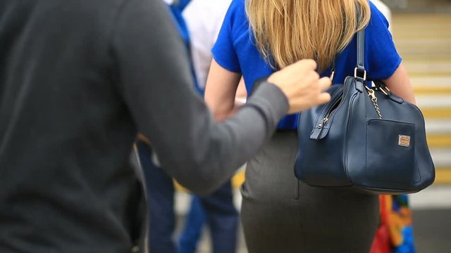 Woman on city street is unaware that her purse has been stolen by crafty pickpocket. She crosses the road through a pedestrian crossing. The thief stole her wallet from the bag
