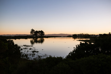 Obraz na płótnie Canvas Sunrise over lake with trees