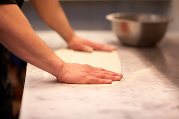 Fototapeta na wymiar chef hands preparing dough on table at kitchen