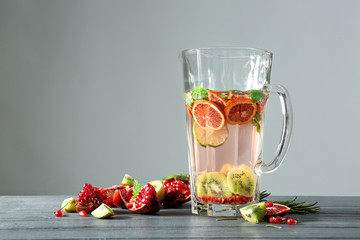 Glass jug with fresh citrus cocktail on table