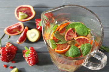 Glass jug with fresh citrus cocktail on table