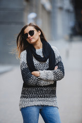 Girl in warm knitted sweater posing on camera in old street of europe