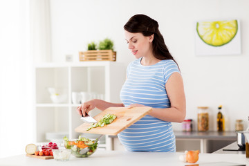 Obraz na płótnie Canvas pregnant woman cooking vegetable salad at home
