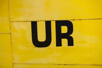 Letters on a yellow painted metal texture with rivets