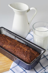 Homemade gluten free bread with linseed flour and psyllium husk. Jug and glass of milk