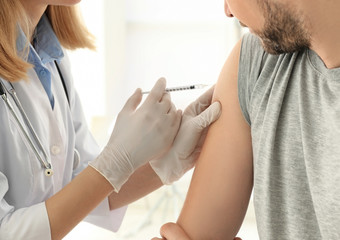 Vaccination concept. Female doctor vaccinating young man