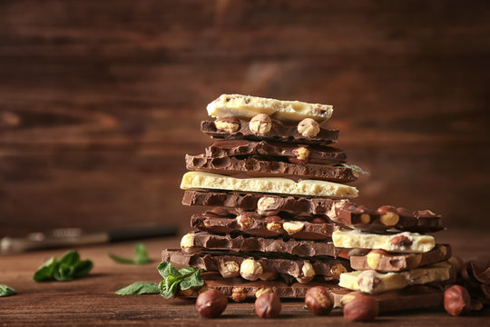 Stack of chocolate bars with nuts on wooden table