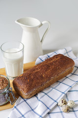 Homemade gluten free bread with linseed flour and psyllium husk. Jug and glass of milk