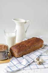 Homemade gluten free bread with linseed flour and psyllium husk. Jug and glass of milk