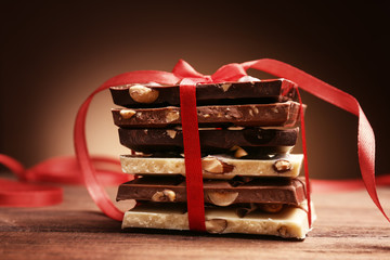 Pile of chocolate tied with ribbon on brown background