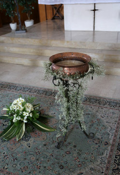 Small baptismal font in copper decorated with flowers during the