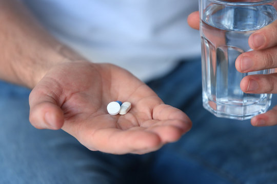 Male hands with pills and glass of water, closeup