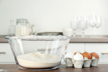 Fototapeta na wymiar Bowl with flour and eggs on kitchen table