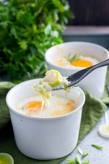 Obraz na płótnie Canvas Breakfast with eggs baked with onion in porridge bowls, selective focus
