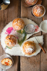 Close up of freshly baked almond and apricot muffins sprinkled with sugar powder and almond petals in a rustic setting on the decorated wooden board.