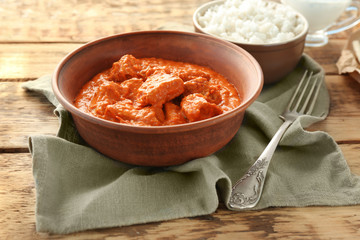 Tasty Murgh Makhani in bowl on wooden background