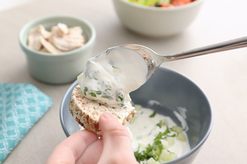 Hand of woman eating tasty yogurt in kitchen, closeup