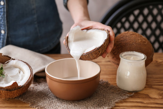 Woman pouring coconut cream into bowl on table
