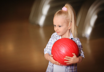 Fototapeta na wymiar Cute child with ball in bowling club