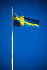 Sweden flag against clear blue sky in bright sunshine
