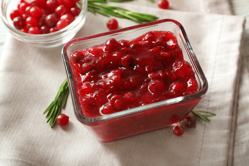 Delicious cranberry sauce in glass bowl on wooden background