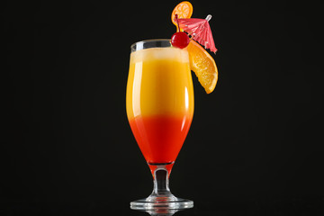 Tequila Sunrise cocktail in glass on black background