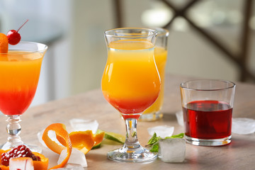 Glasses of Tequila Sunrise cocktail with ingredients on table