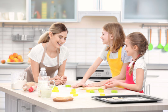 Young woman and her daughters cooking in kitchen