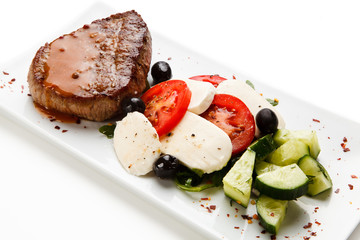 Grilled steak with mozarella and vegetables on white background
