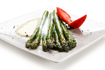 Grilled asparagus with sauce on white plate