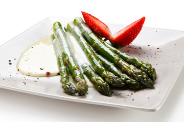 Grilled asparagus with sauce on white plate
