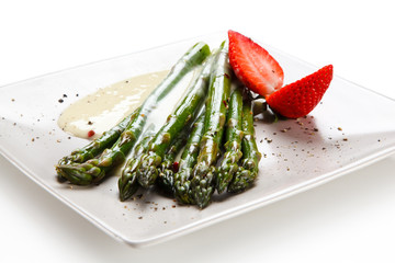 Grilled asparagus with sauce on white plate